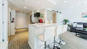 Une cuisine moderne dotée d’un îlot central, de tabourets de bar et d’un coin salon avec un canapé et une table basse.