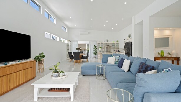 Un salon spacieux avec un grand téléviseur à écran plat, un canapé bleu et une table basse blanche.
