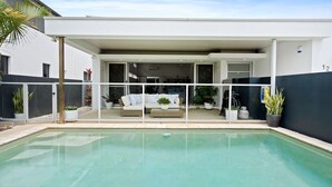 Une maison moderne dotée d’une piscine, d’un patio couvert et du chiffre « 12 » peint sur le mur.