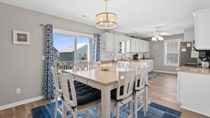 Une cuisine moderne avec des meubles blancs, un îlot central et un coin repas comprenant une table et des chaises.