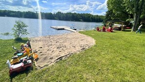 Un cadre idyllique au bord du lac, avec un quai, une pelouse et une petite construction abritant des chaises.