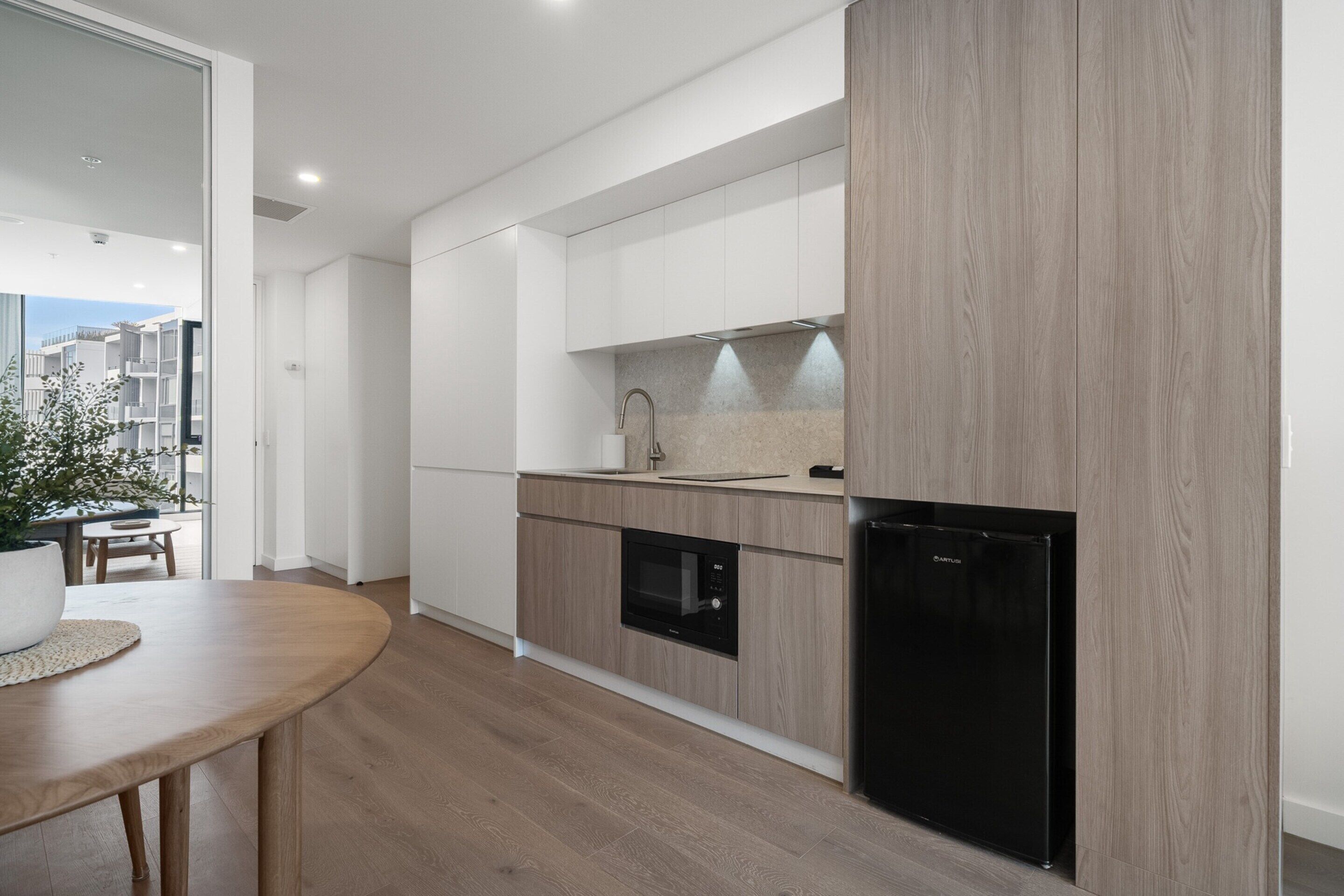 A modern kitchen with built-in appliances, a wooden countertop, and a dining area with a table and chairs.