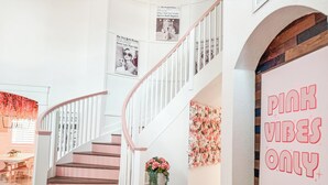 Una escala amb graons rosats, un element decoratiu floral a la paret, i un cartell que diu "PINK VIBES ONLY".
