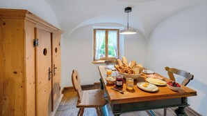 A dining area with a wooden table set for breakfast, including bread, eggs, and fruit. - Stube & Stories - Heritage Riverside Home (Garmisch-Partenkirchen)