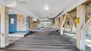A covered wooden deck with a hammock, wooden walls, and a caution sign. - Charming dog-friendly cottage w/ Hot Tub, Smart TVs, Community Pool & Pickleball (Avon)