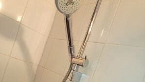 Une douche équipée d’un pommeau de douche à main et d’un flexible de douche.