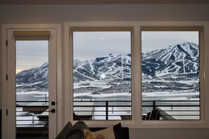 A room with a large window overlooking a snowy mountain landscape.