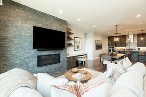 A modern living room with a flat-screen TV, fireplace, and comfortable seating.