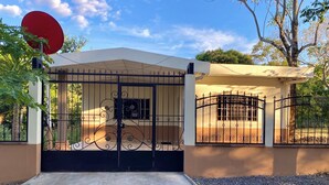 A gated entrance with a satellite dish, a covered porch, and a concrete driveway. - Amazing 3 bedroom house with AC in delightful El Salvador in El Truinfo (El Salvador)