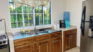 A kitchen with a window, stainless steel appliances, wooden cabinets, and a water dispenser. - Amazing 3 bedroom house with AC in delightful El Salvador in El Truinfo (El Salvador)