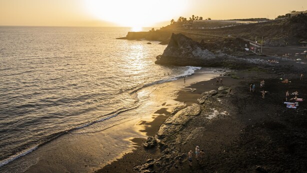 A beach with rocky terrain and a sunset.
