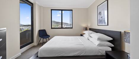 Une chambre d’hôtel moderne, dotée d’un grand lit, d’une chaise, d’un bureau et d’une fenêtre donnant sur la ville.