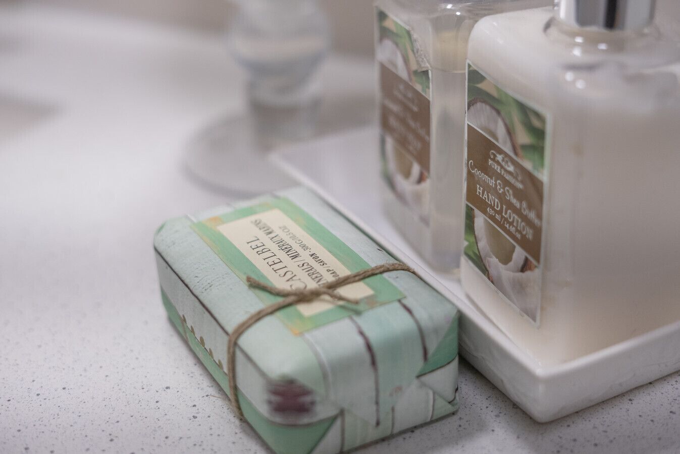 A bar of soap and a bottle of coconut & lemon hand lotion on a countertop.