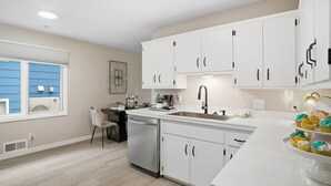 Una cocina moderna con armarios blancos, lavavajillas de acero inoxidable y una isla grande con pileta.