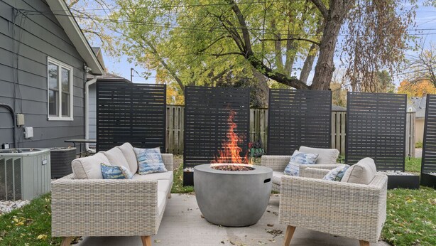 Un patio con mobiliario de mimbre y una chimenea central.