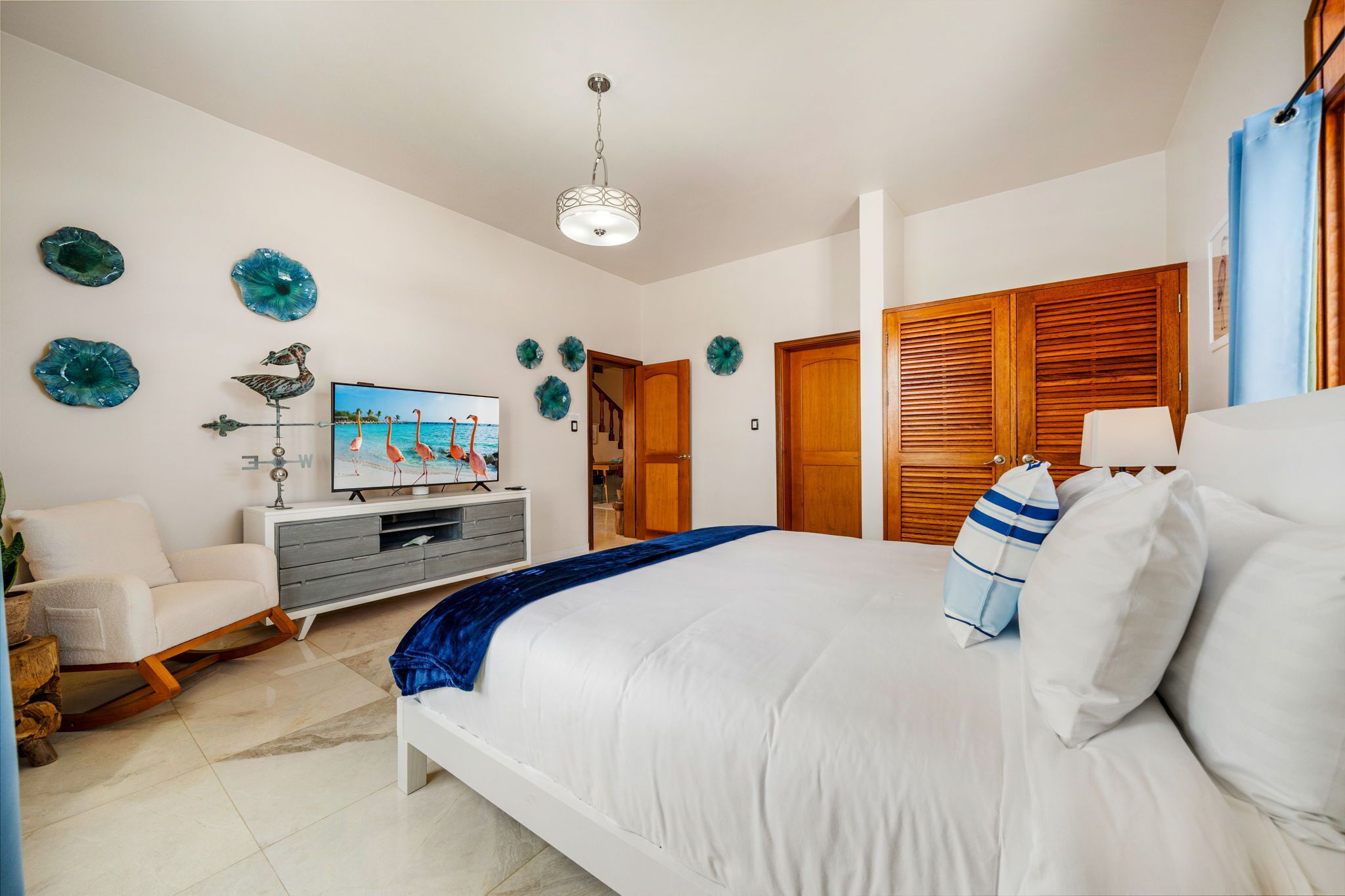 Une chambre à coucher comprenant un lit, un téléviseur, une armoire en bois et des œuvres d’art décoratives accrochées au mur.