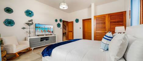 Une chambre à coucher comprenant un lit, un téléviseur, une armoire en bois et des œuvres d’art décoratives accrochées au mur.
