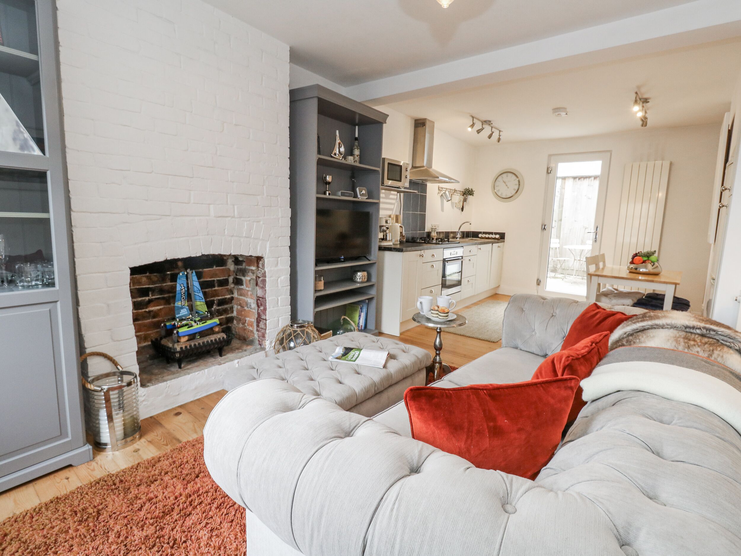 Ein Wohnzimmer mit Kamin, einer Couch und einer Küche im Hintergrund.