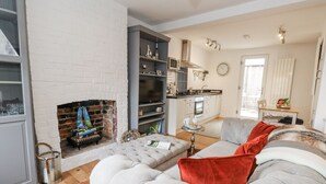 Ein Wohnzimmer mit Kamin, einer Couch und einer Küche im Hintergrund.
