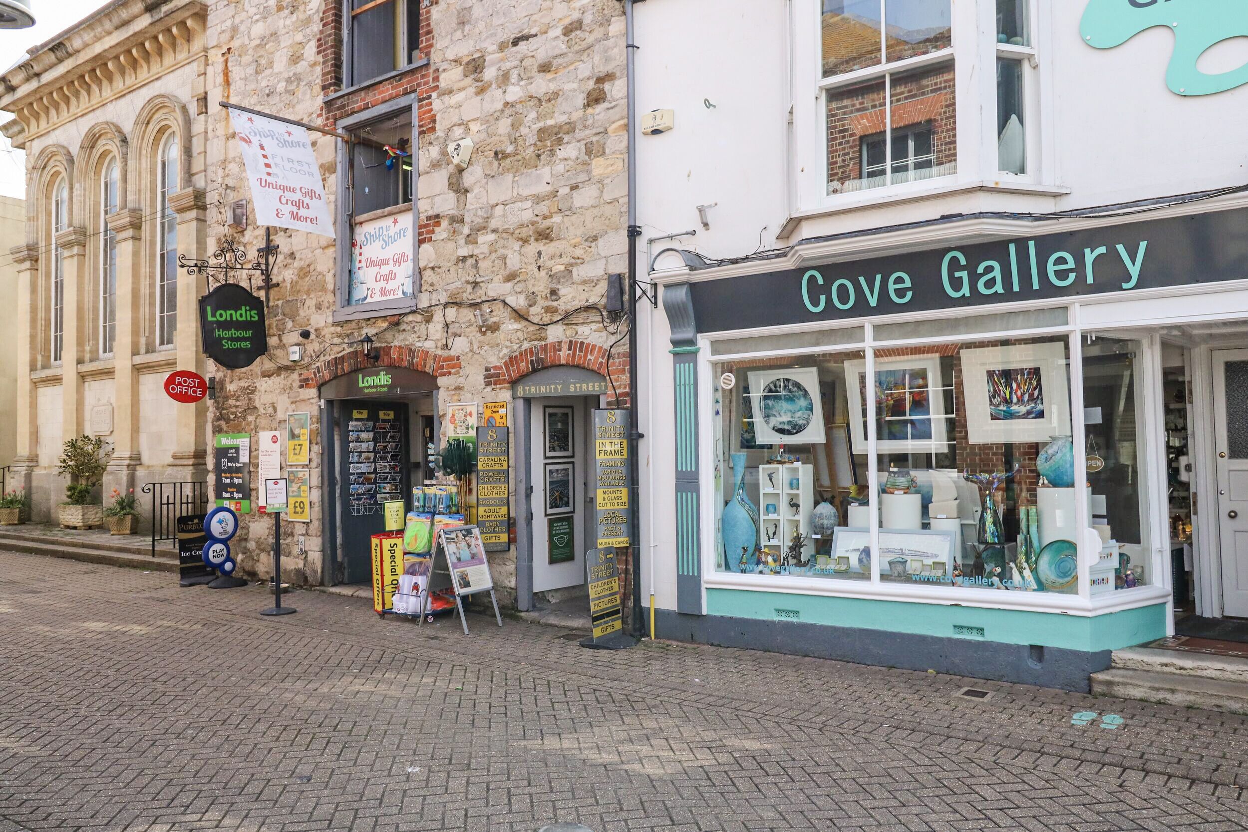 A storefront named Cove Gallery with a display window showcasing various items.