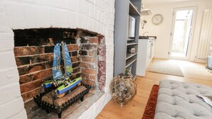Ein Wohnzimmer mit Kamin aus Ziegeln, einem Fernseher und einer Couch.