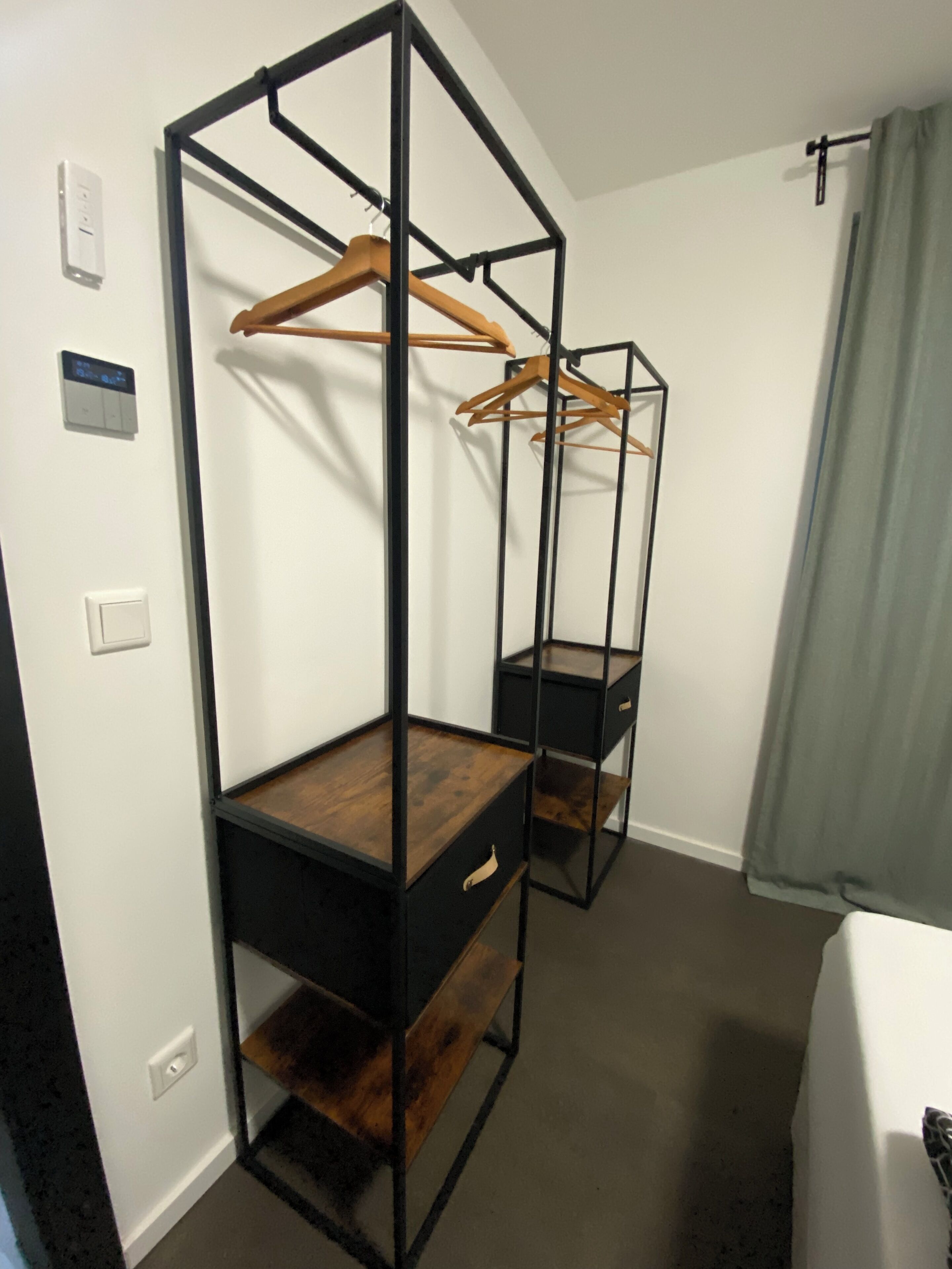A room with a built-in wardrobe featuring wooden shelves and a hanging rack.