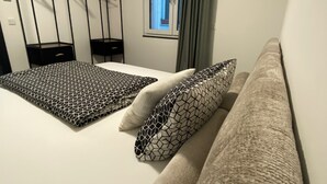 Un dormitorio con cama, sofá, armario y ventana con cortinas.