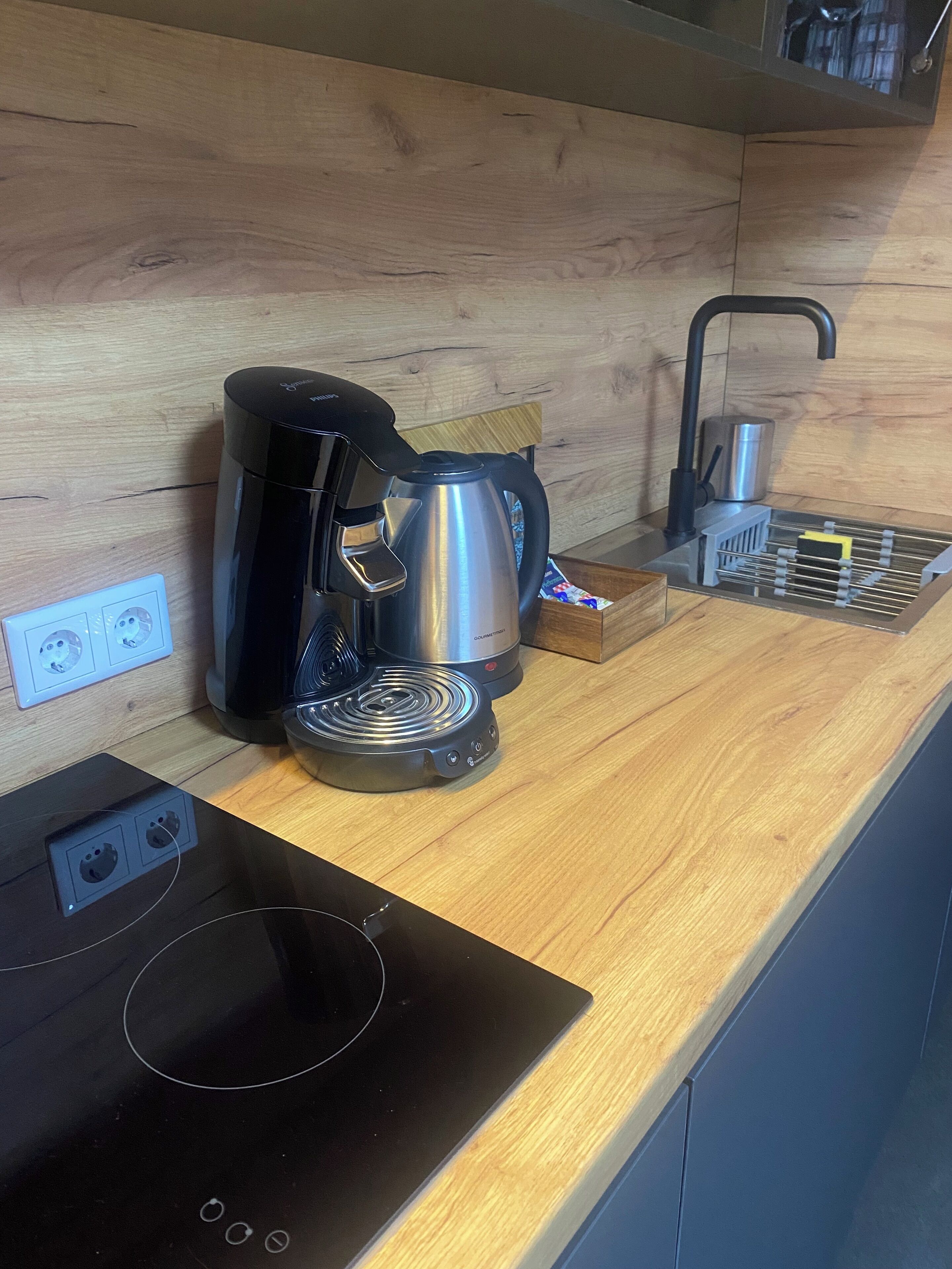 Eine Küche mit Kaffeemaschine, Wasserkocher und integriertem Induktionskochfeld.