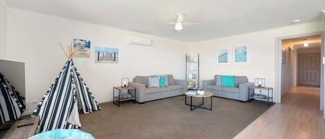 A modern living room with a sofa set, a coffee table, and a tent-like structure.