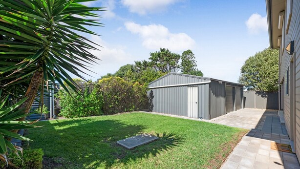 A backyard with a small shed, a lawn, and a concrete pathway. - Spacious 3-bed Ground Level Beachside Stay (Middleton)