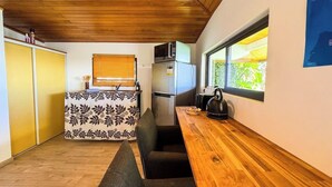 A compact kitchen with a wooden countertop, a built-in microwave, and a refrigerator.