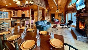 Ein geräumiges Ferienhaus mit Essbereich, gedecktem Tisch und einem gemütlichen Wohnzimmer mit Kamin und großem Fernseher.