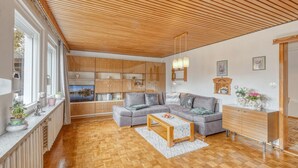 A spacious living area with a wooden ceiling, built-in wooden cabinets, a grey sofa, a wooden coffee table, and a view of a cityscape through large windows. - Stunning home in Schwerin with WiFi (Schwerin)