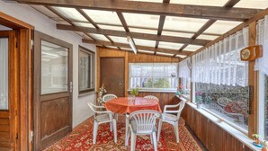 A covered patio with a wooden ceiling, a table with chairs, and a window with lace curtains. - Stunning home in Schwerin with WiFi (Schwerin)