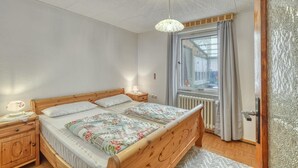 A bedroom with a wooden bed, a nightstand, a lamp, a window with curtains, and a radiator. - Stunning home in Schwerin with WiFi (Schwerin)