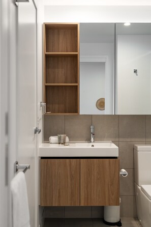 A modern bathroom with a wooden vanity, a white sink, and a mirror. - Spacious West End Apartment With Pool & BBQ Access (Brisbane)