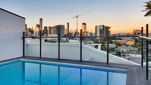 Een dakzwembad met uitzicht op de skyline van de stad, inclusief hoogbouw en een bouwkraan.