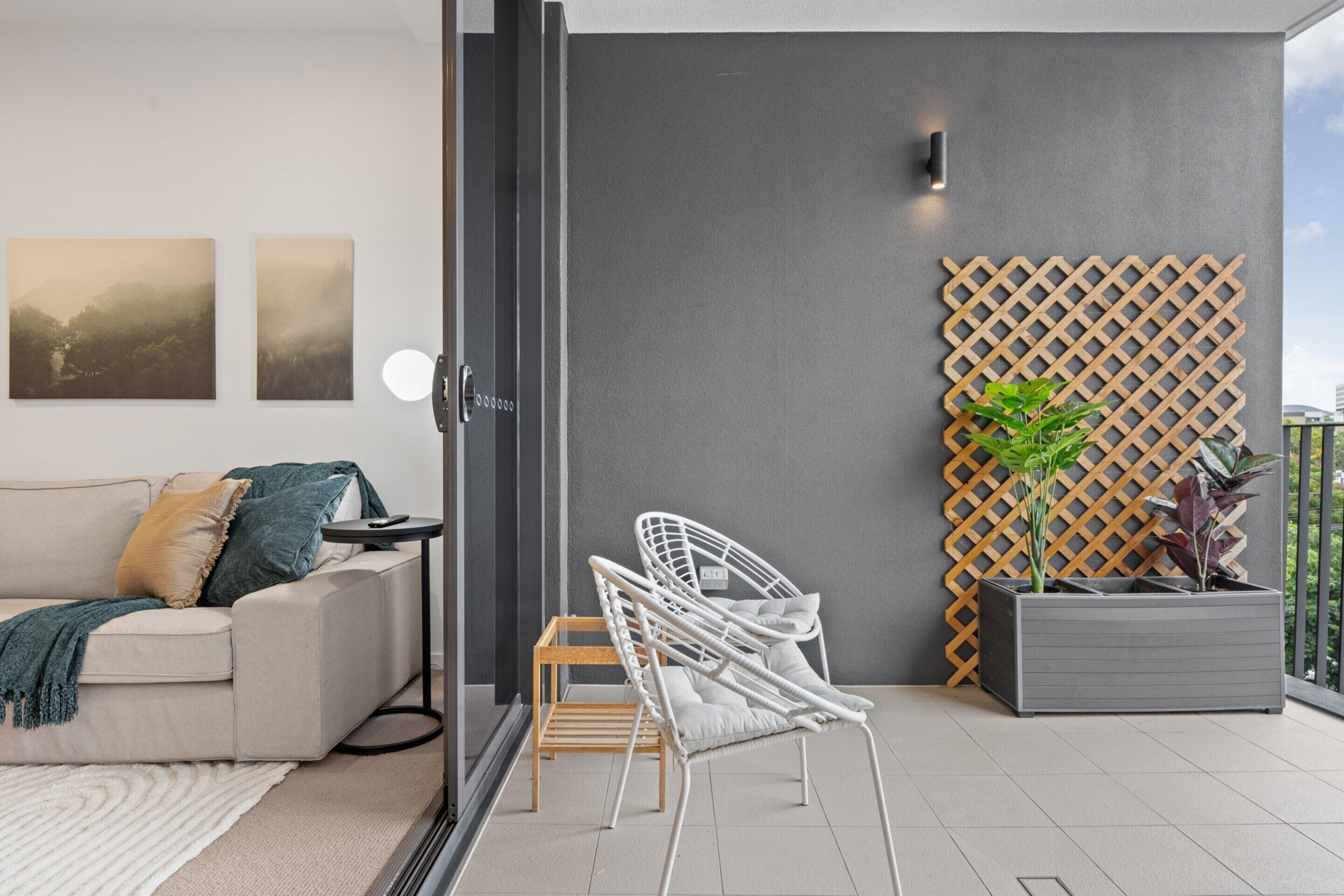 A modern living room with a sofa, a white chair, a small table, and a grey planter with plants.