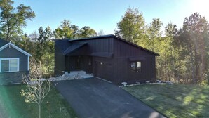 A modern two-story house with a dark exterior, a front driveway, and a small front yard. - Villa 1 on Preserve Golf Course! (Pequot Lakes)