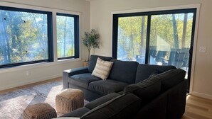 A modern living room with a sectional sofa, two ottomans, and a potted plant. - Villa 1 on Preserve Golf Course! (Pequot Lakes)