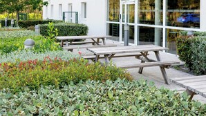 Un patio con mobiliario exterior y un edificio con grandes ventanales.