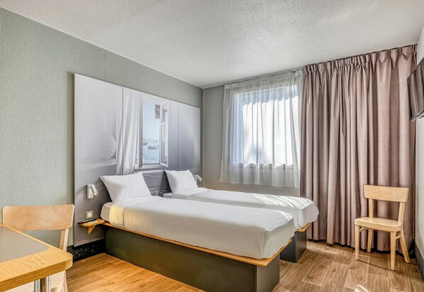 A hotel room with a bed, bedside tables, a chair, and a window with curtains. - B&B Hotel Bordeaux Sud Mios (Mios)