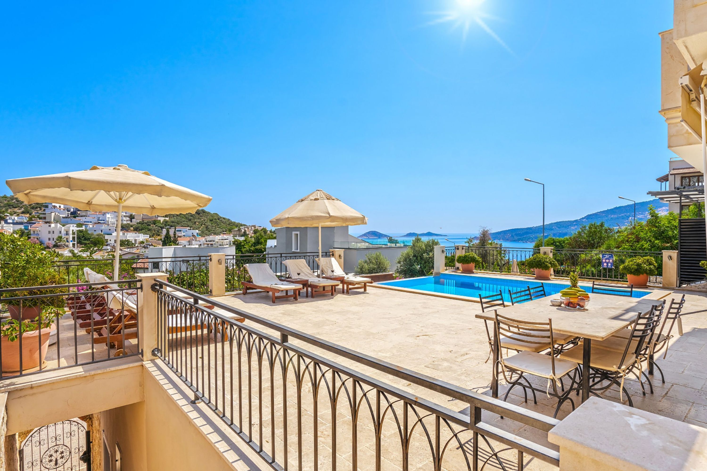Un área de piscina en la azotea con sillones, sombrillas y vistas al mar.