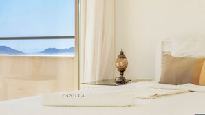 Un lit bien fait, avec un oreiller blanc sur lequel est inscrit le mot « VANILLE », et une lampe décorative posée sur une table de chevet.