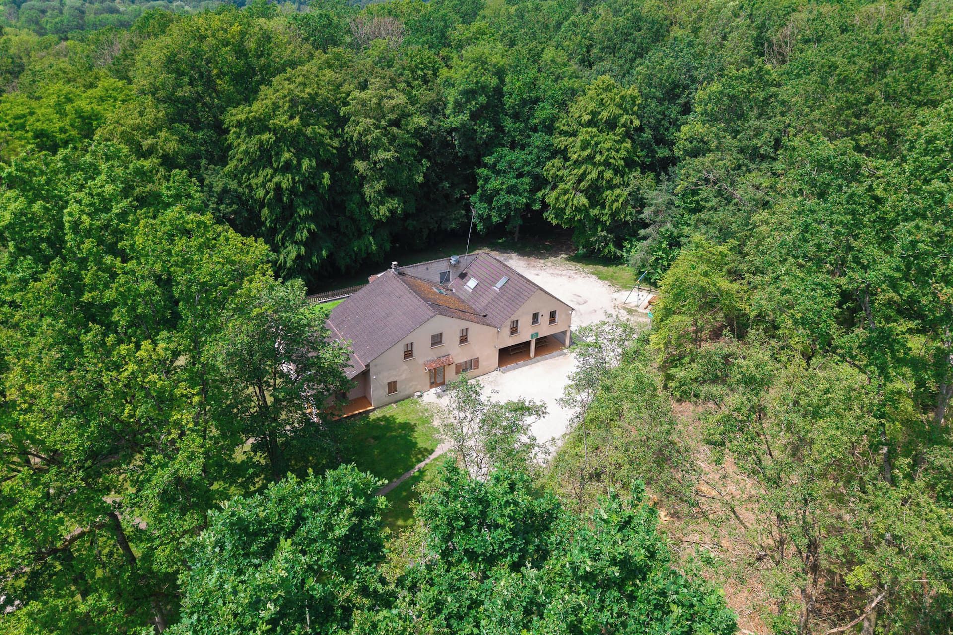 A single-story building with a sloped roof, surrounded by dense forest.