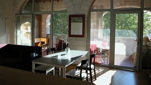 A dining area with a table and chairs, large arched windows, and a view of the outdoors.