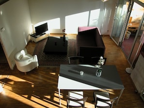 Un salon moderne avec un canapé, un téléviseur et une table à manger avec des chaises.