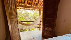 A room with a hammock under a wooden ceiling, a bed, and a view of greenery outside. - Big Bambu (Porto Seguro)