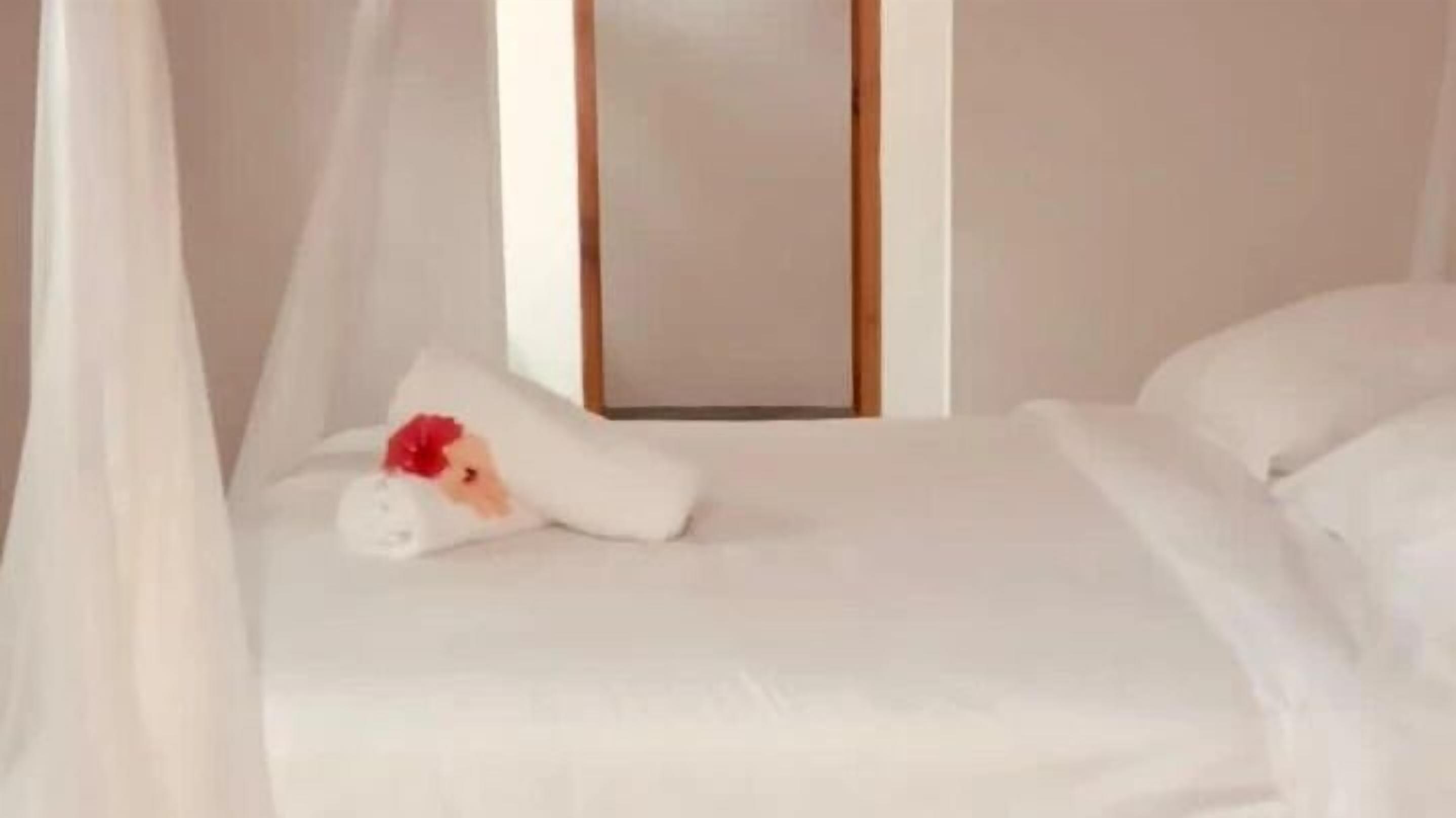 Een bed met witte lakens en een hemelbed.