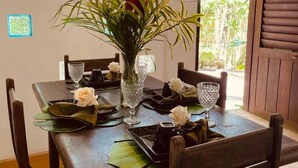 A dining table set with plates, glasses, and a vase with flowers. - Big Bambu (Porto Seguro)